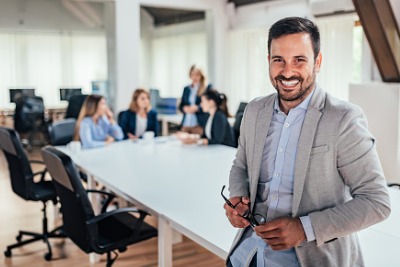 smiling business owner with colleagues at conference table in background